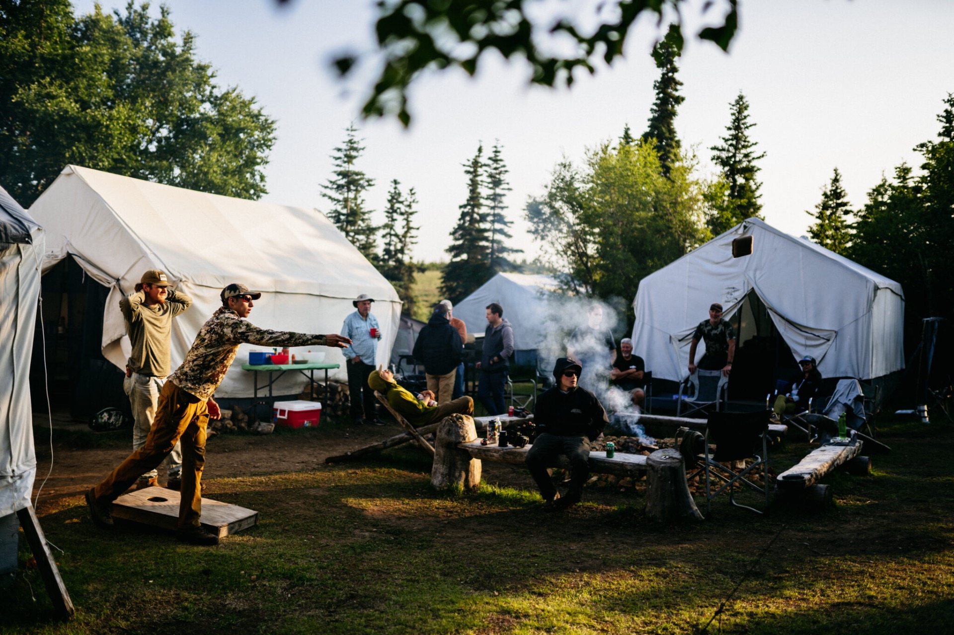 Guests playing cornhole around the fire pit at the wilderness camp