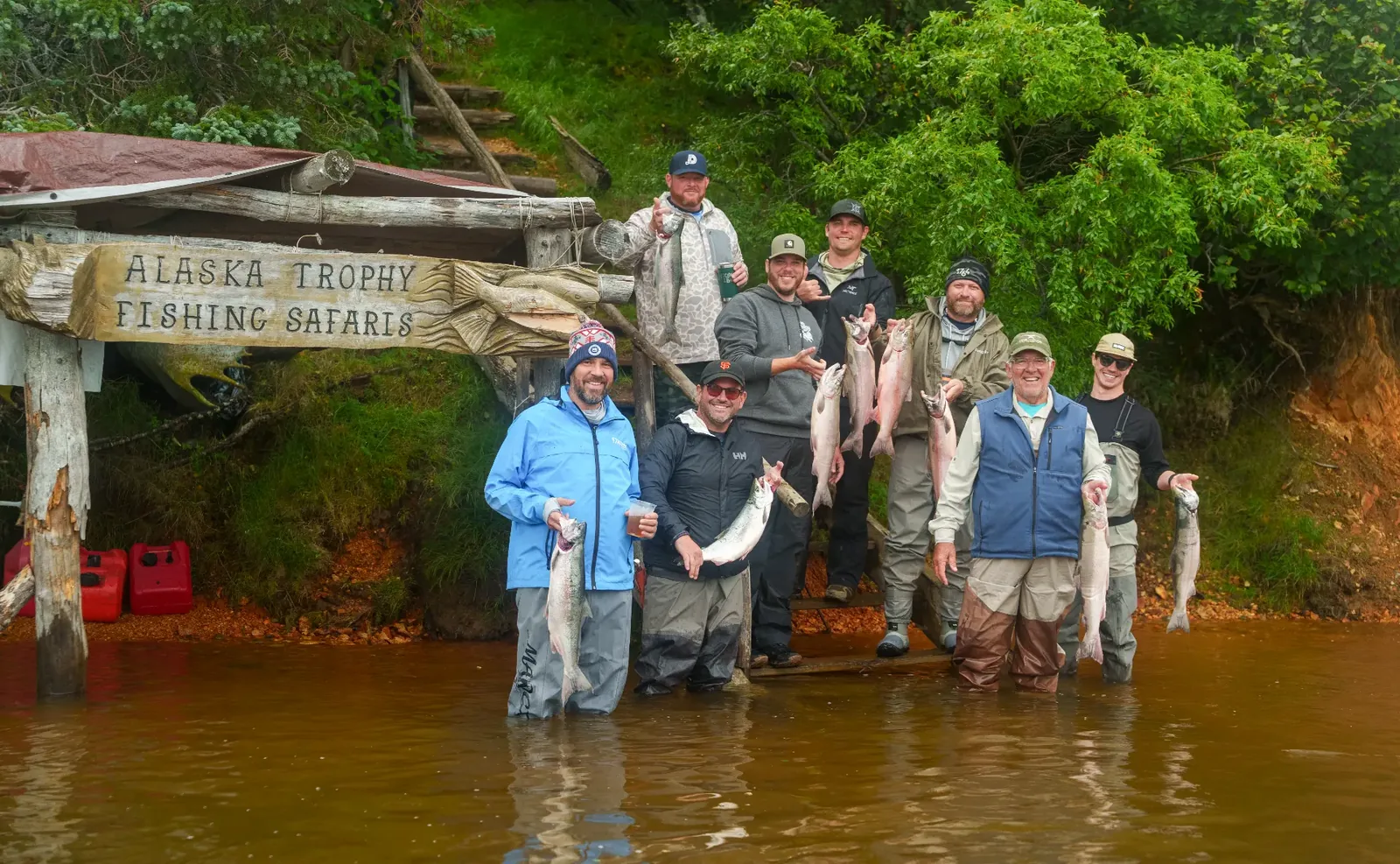 Guests holding their salmon catch beneath the Alaska Trophy Fishing Safaris sign